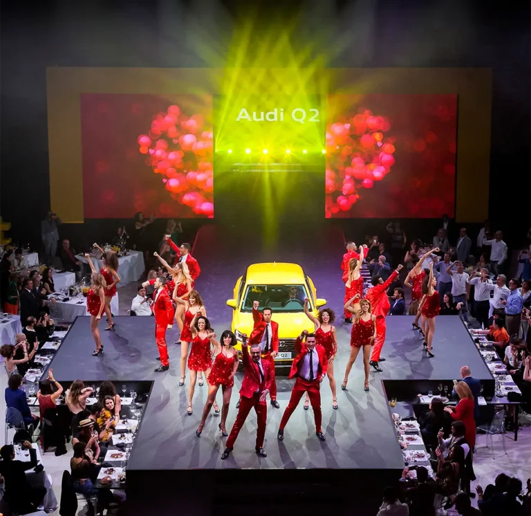 Vista desde arriba del escenario de la presentación del Audi Q2, con bailarines, el coche y las mesas de la cena alrededor