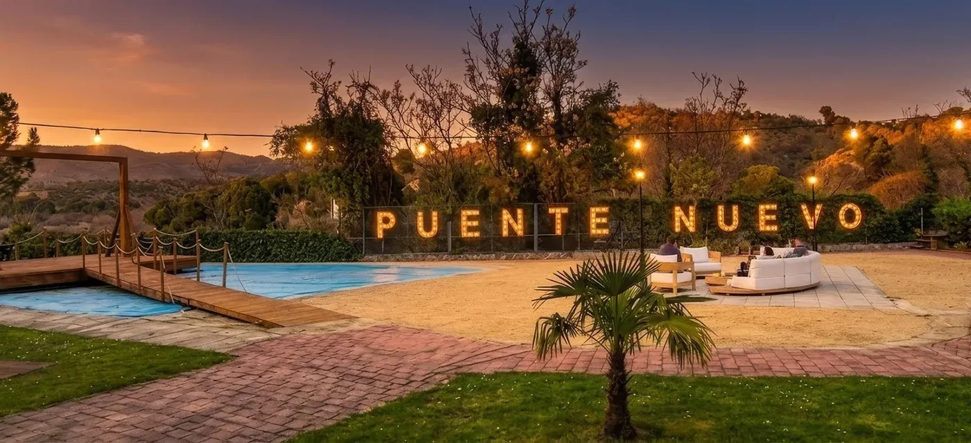 Campus Puente Nuevo al atardecer, con el letrero iluminado y la piscina