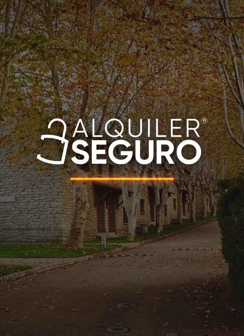 Logotipo de Alquiler Seguro en blanco sobre una avenida arbolada de Campus Puente Nuevo en otoño