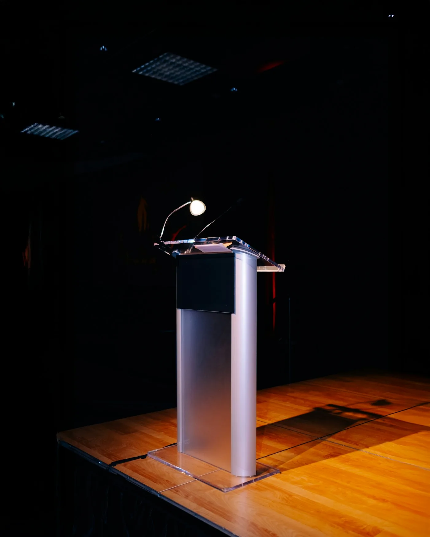 Atril con micrófono iluminado sobre el escenario, preparado para la ponencia