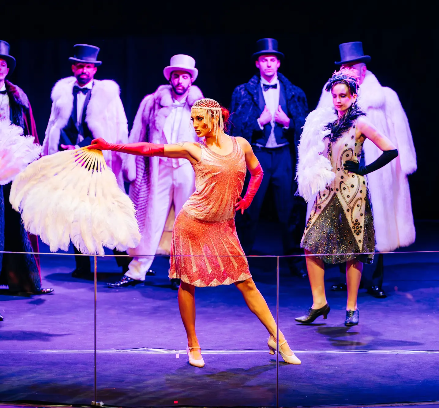Bailarinas con abanicos de plumas y actores con sombrero de copa en una cena temática de los años 20