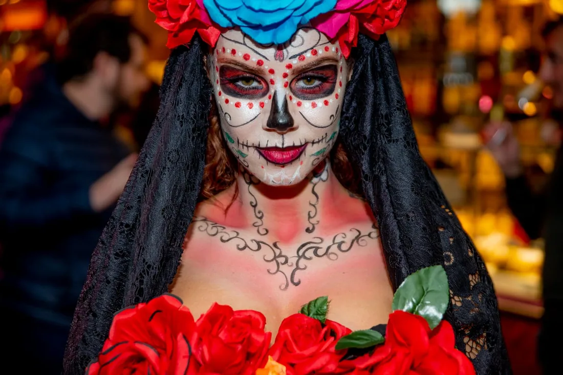 Catrina con maquillaje del Día de Muertos y corona de flores en una cena temática mexicana