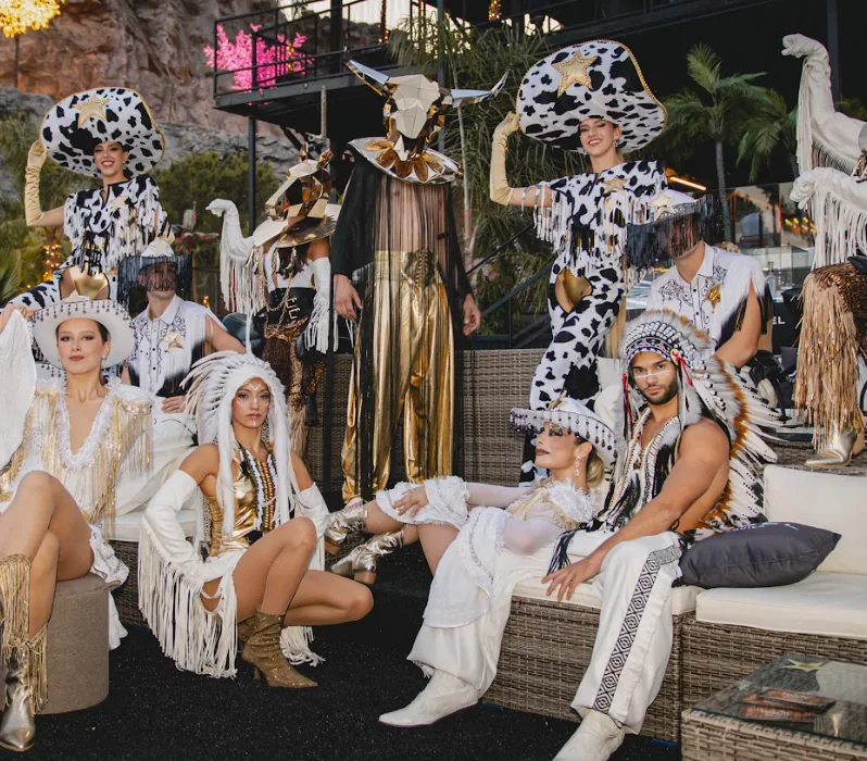Artistas con sombreros vaqueros, flecos y plumas en una fiesta temática del Lejano Oeste