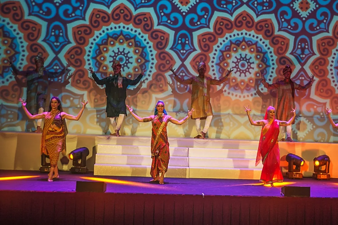 Bailarines con vestuario de la India sobre un escenario con proyección de mandalas