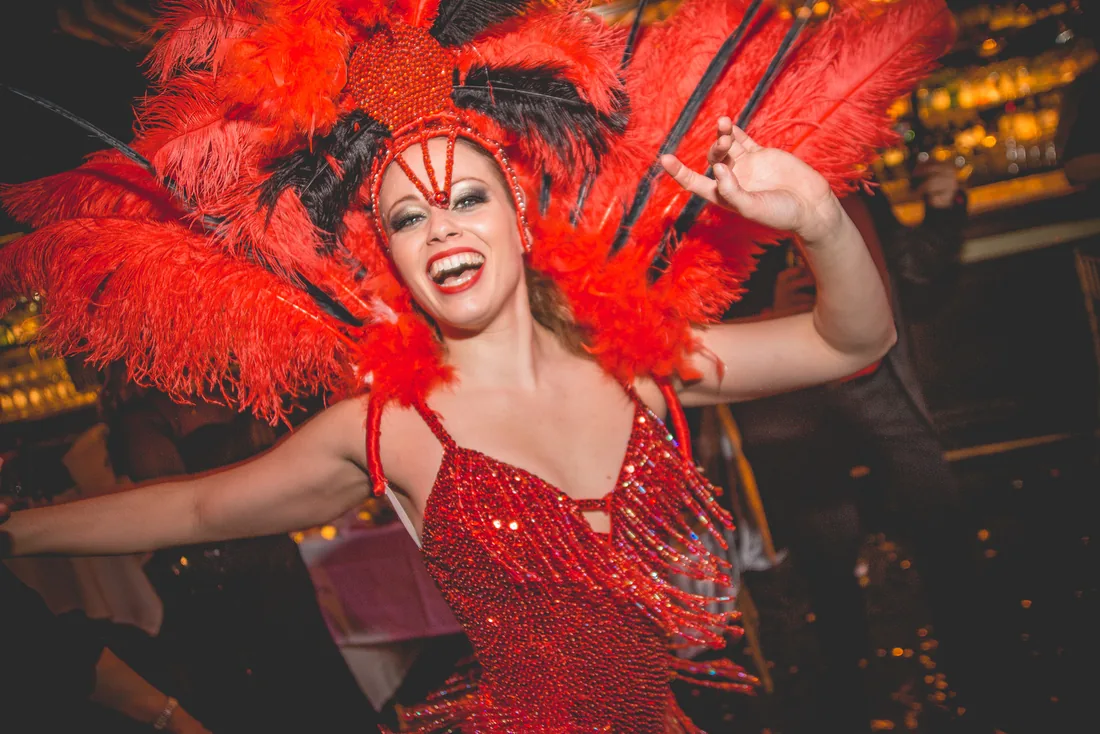 Bailarina con tocado de plumas rojas y vestido de lentejuelas en una noche de ritmo latino para empresas