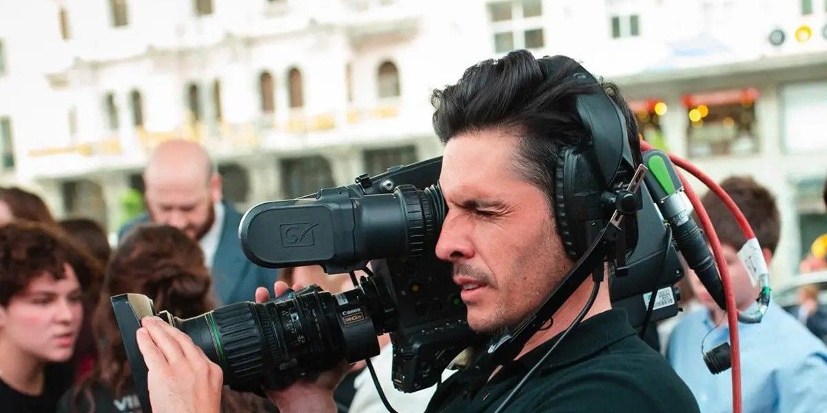Técnico de cámara con auriculares grabando un evento en la calle