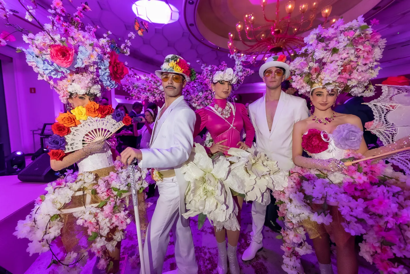 Artistas con vestuario de flores de primavera y sombreros blancos en una gala de empresa