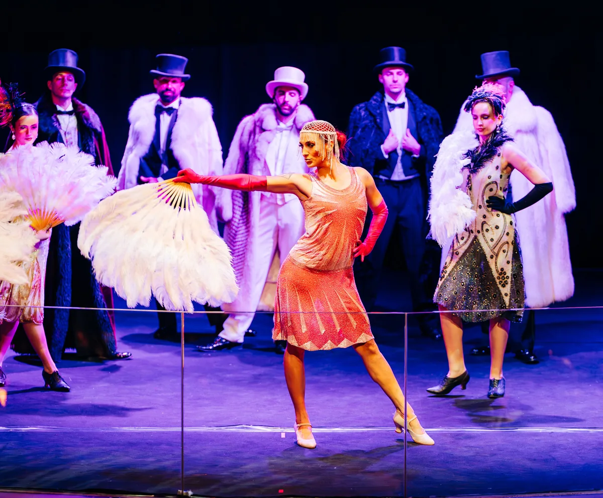 Bailarinas con abanicos de plumas y actores con sombrero de copa en un espectáculo de los años 20 para empresas