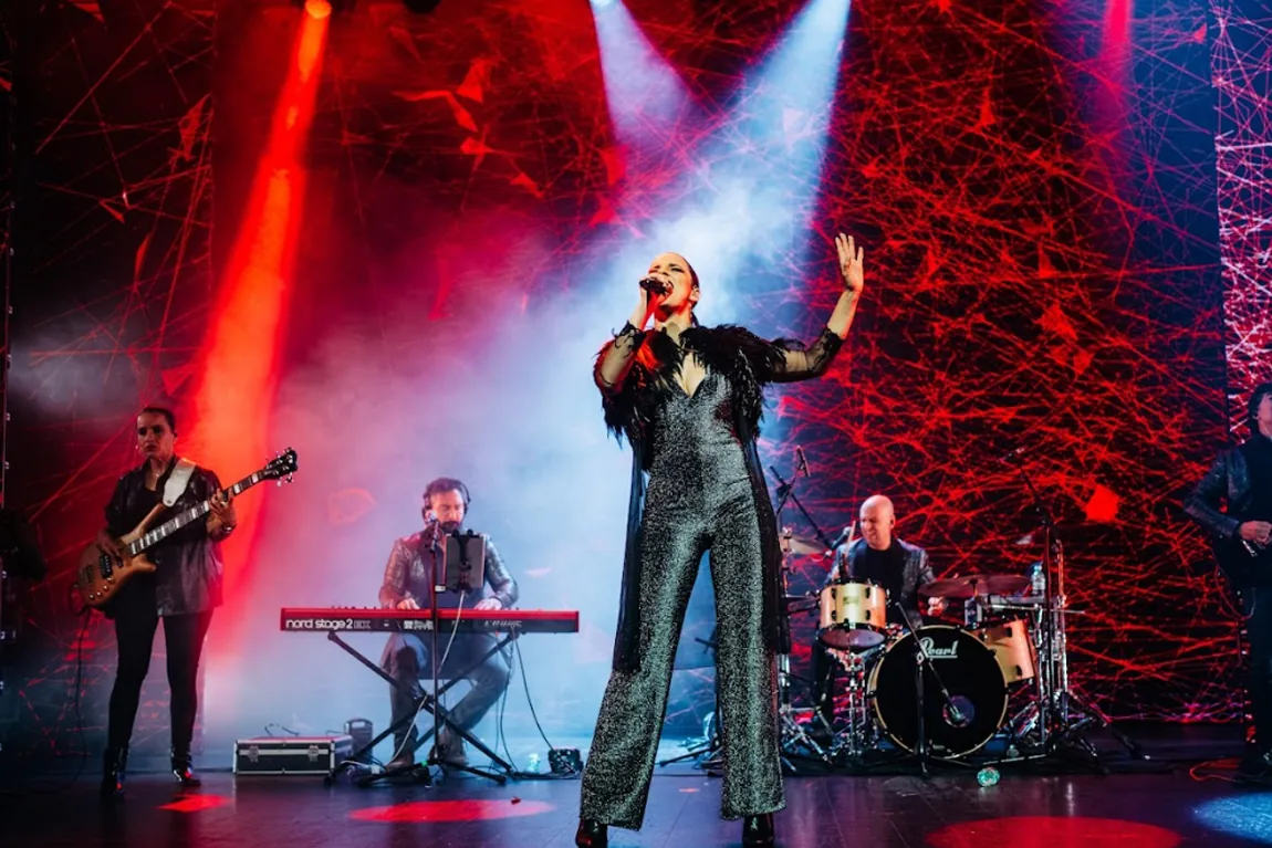 Cantante y banda en directo sobre un escenario con luces rojas en una fiesta de empresa