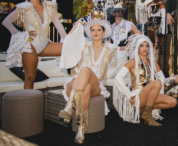 Artistas con sombreros vaqueros, flecos dorados y botas camperas en un show del Lejano Oeste