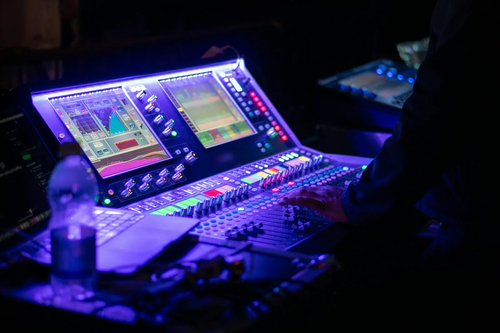 Técnico de sonido manejando una mesa de mezclas digital durante un evento en directo