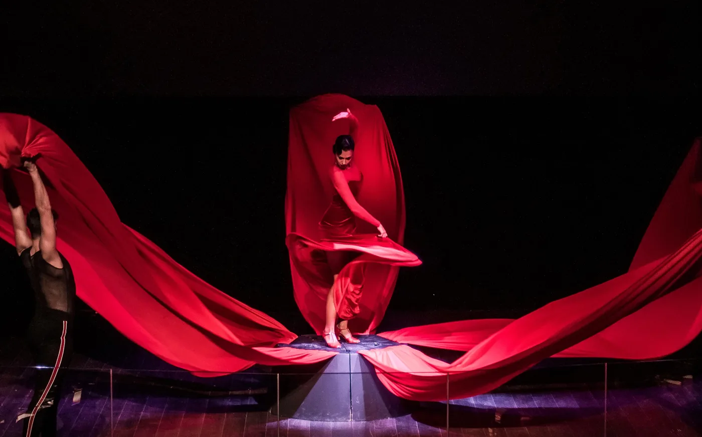 Bailaora envuelta en una gran tela roja en el centro del escenario