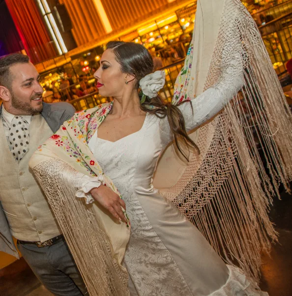 Bailaora con mantón de Manila y bailaor con chaleco en una noche de baile español