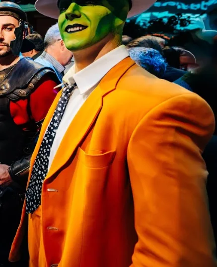 Actor caracterizado con máscara verde y traje naranja entre los invitados de una noche de cine