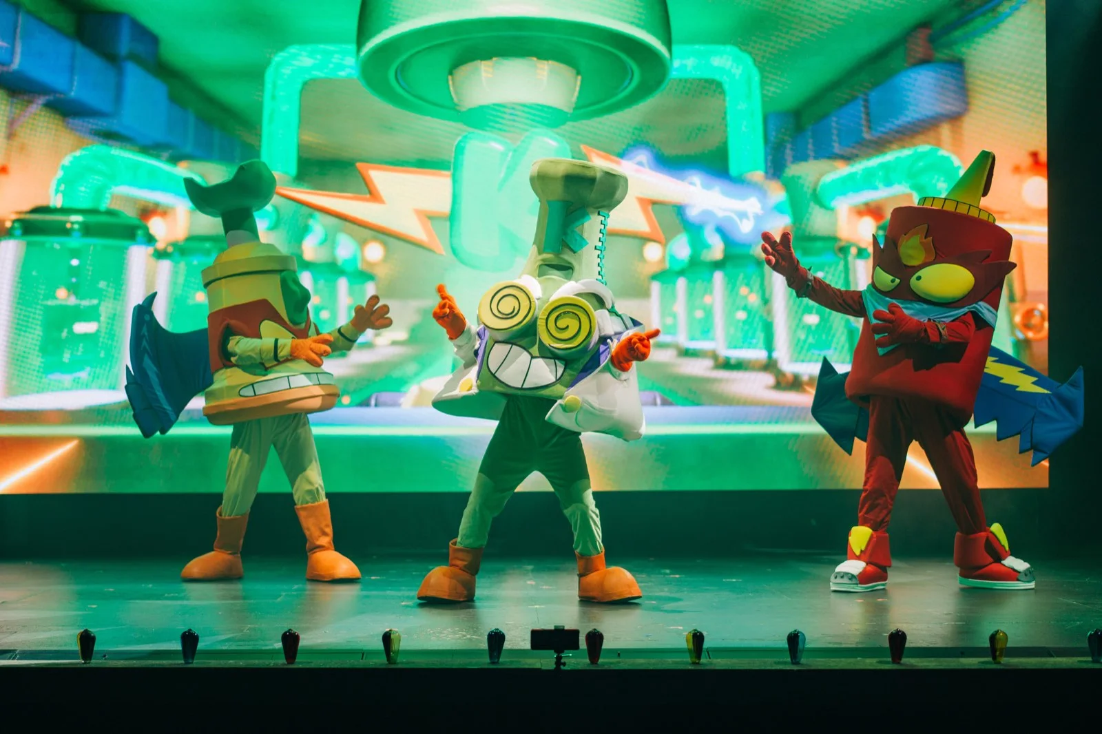 Personajes de SuperThings en un laboratorio proyectado en la pantalla del escenario