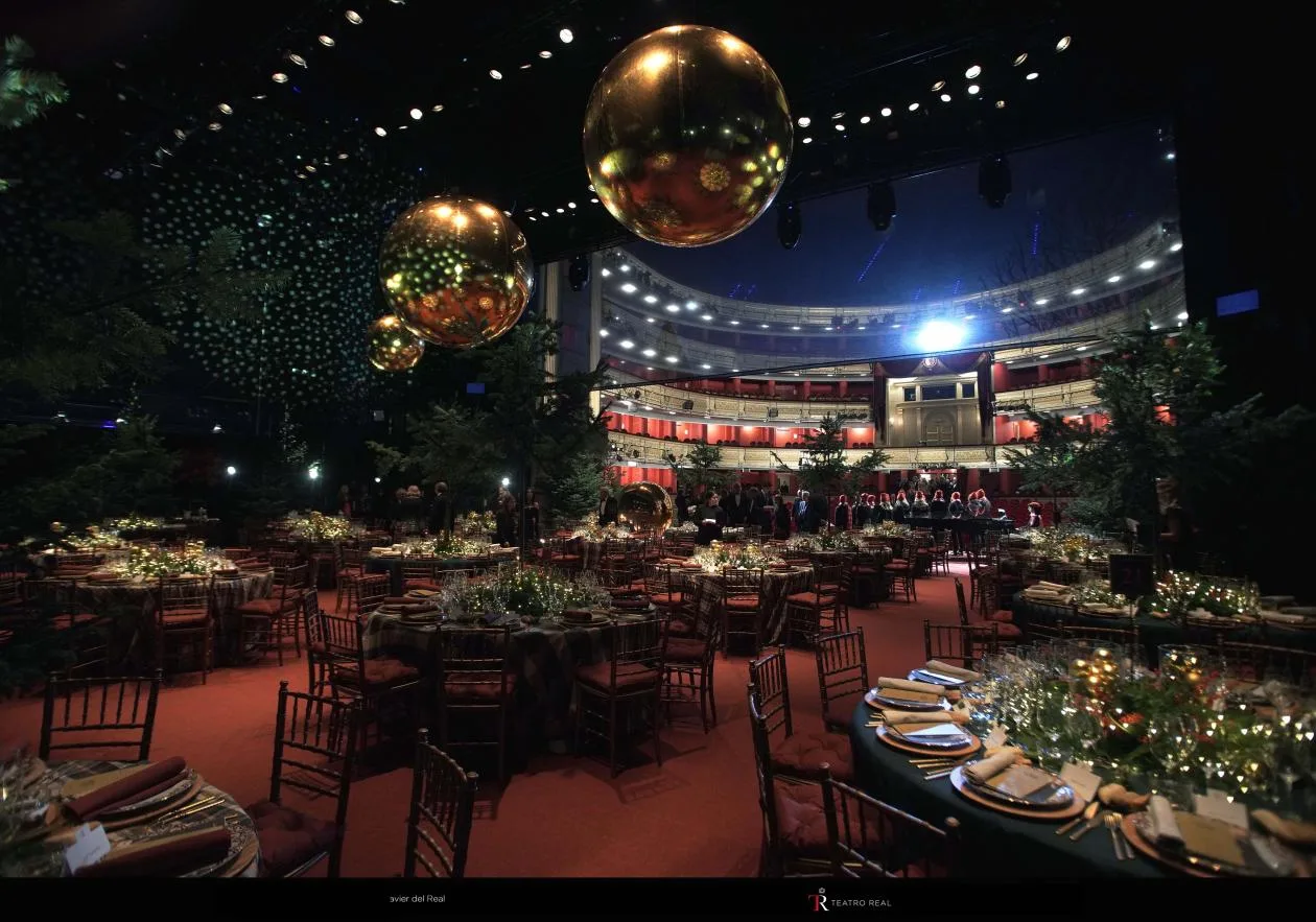 Cena de gala con mesas redondas sobre el escenario del Teatro Real iluminado